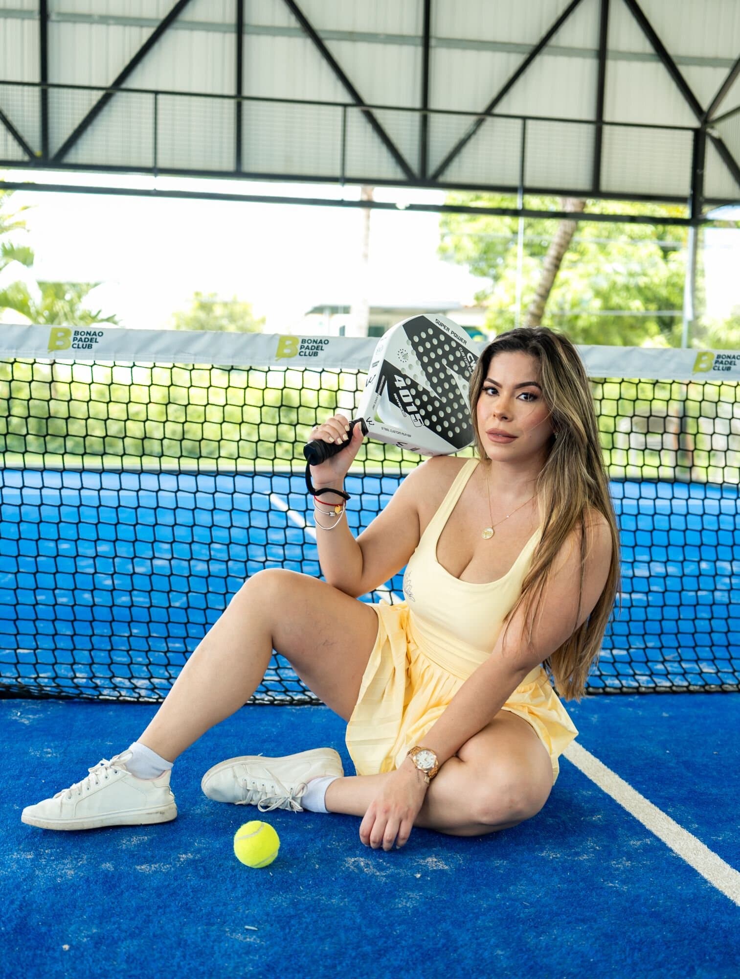 Enterizo Dalia — en Amarillo, sentada en la cancha de pádel